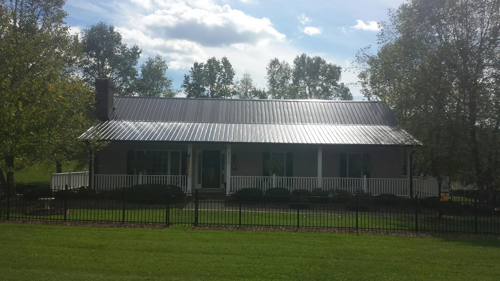 Gray metal roof on a brick ranch with a full width front porch — Gutter Guard Installation work by our crew in Kearney