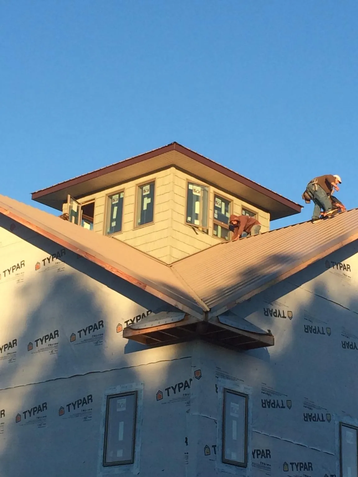 Roofers working around a rooftop cupola on a new metal roof at sunset — Roof Waterproofing in Kearney by Roofing Brothers